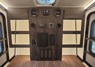 Interior view of the CORE RV 5510 front cabinet with 6 cubbies, 2 overhead cabinets, bluetooth speakers and heating vents and outlet