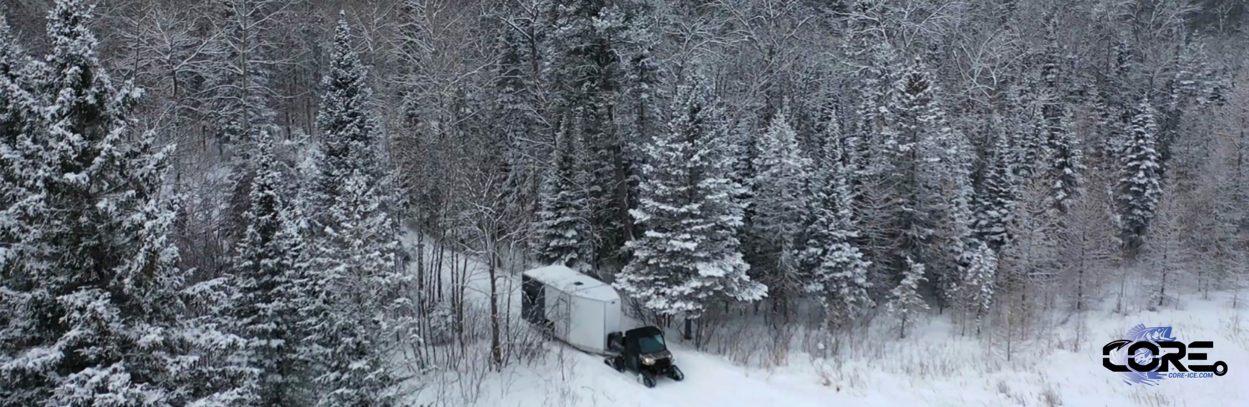 A CORE ICE trailer being pulled behind a side by side through the woods, winter scene, onto the ice in winter to ice fish
